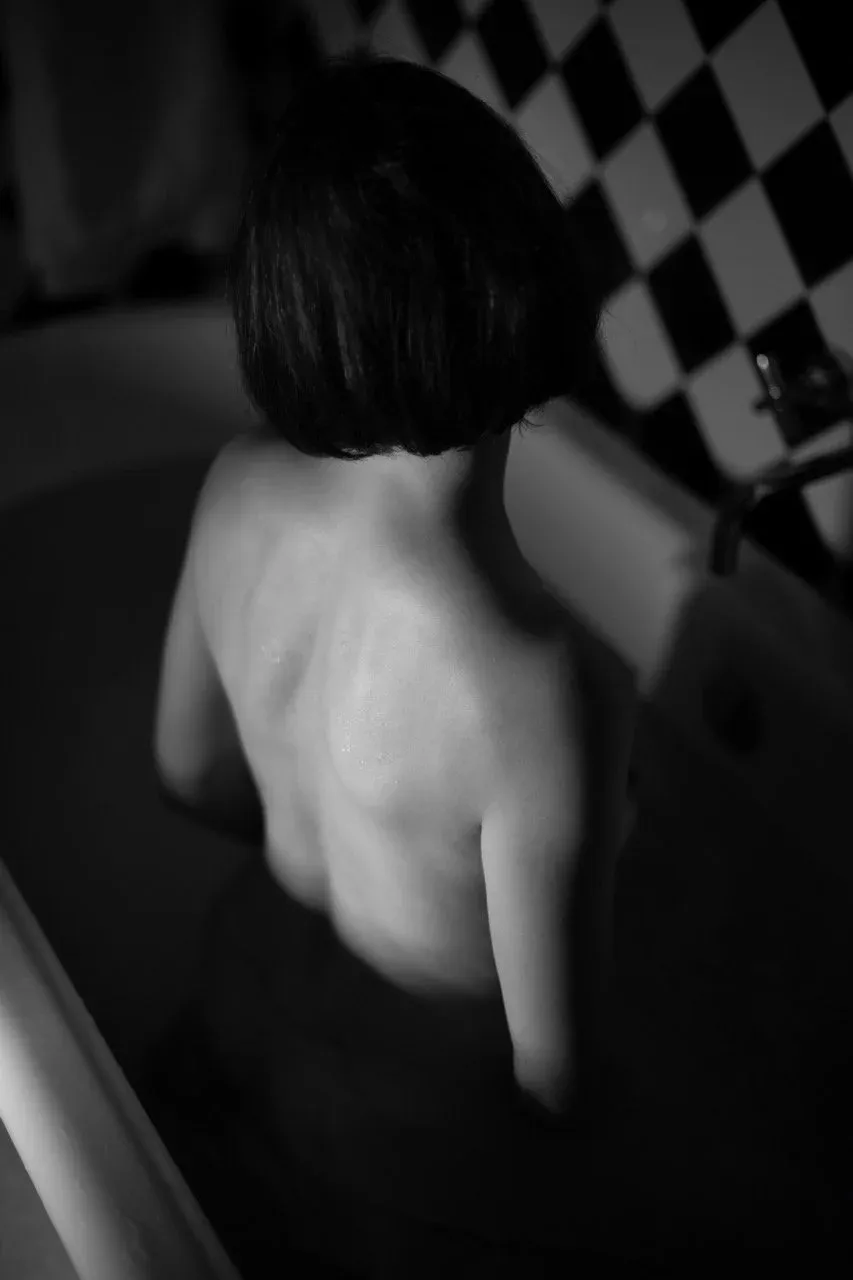 How to Capture Artistic Nude Photos in the Shower: Silhouetted nude female figure standing in the shower, dramatic lighting outlining her body with water droplets glistening.